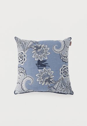 Square blue cushion with white and navy floral and paisley patterns on fabric surface against white background.