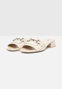 Tacchi beige aperti con finitura in pelle liscia, caratterizzati da una decorativa fibbia argentata e un tacco basso a blocco.