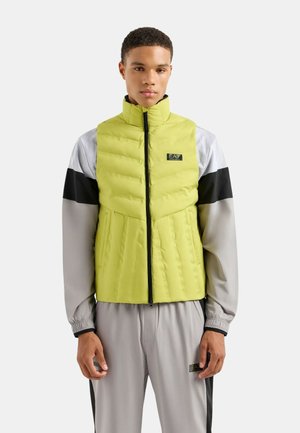 Pudset vest i lys limegrøn med høj krave og frontlynlås, med sorte og grå accenter på skuldrene og siderne.