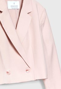 Jasnoróżowa krótka marynarka z gładkiej tkaniny, z dwoma guzikami z przodu, szpiczastymi klapami i minimalistycznymi detalami.