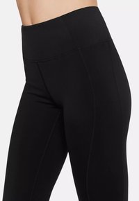Black high-waisted leggings feature a smooth texture, flat seams, and a form-fitting design, suitable for activewear and casual use.