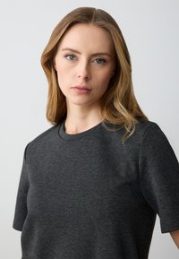 Donkergrijze t-shirt met korte mouwen, gemaakt van een zachte, gladde stof, met een klassieke ronde hals en een minimalistisch ontwerp.