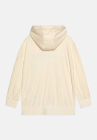 Sudadera de canalé color crema con capucha ajustable, mangas largas y puños y dobladillo elásticos. La tela tiene un aspecto suave y texturizado.