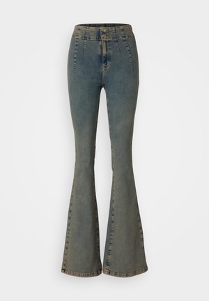 High-waisted flared jeans in faded blue denim, featuring double buttons, vertical stitching, and a slightly worn texture at the hems.