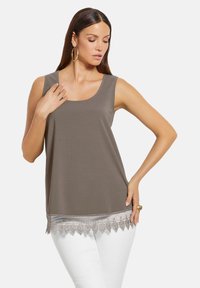 Brauner ärmelloser Oberteil mit rundem Ausschnitt, der am Saum mit Spitzenbesatz verziert ist. Der Stoff ist glatt und die Passform ist locker.