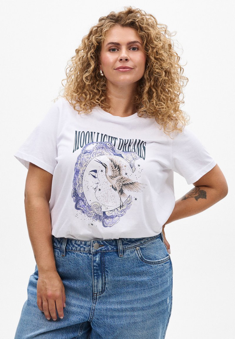 Weißes Baumwoll-T-Shirt mit einem grafischen Design eines Mondes, eines Vogels und dem Text "MOON LIGHT DREAMS" in Grün, kombiniert mit blauen Jeans.