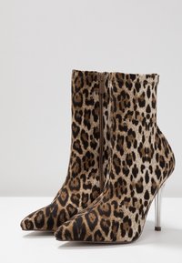 Bottines en imprimé léopard en tissu doux, avec un bout pointu, une fermeture éclair et un talon transparent.