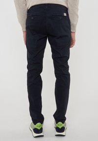 Pantaloni blu navy a taglio slim, realizzati in cotone, con una texture liscia, due tasche posteriori e un'etichetta del marchio sulla vita.