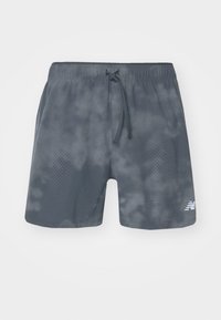 Shorts de sport gris avec un cordon de serrage, fabriqués en tissu texturé, présentant des motifs à pois sur un côté et un logo en bas à droite.