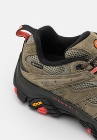 GORE-TEX tursko med sko, med en øvre del i brun semsket skinn, mesh-detaljer, svart gummisåle, oransje og røde detaljer, og en teksturert overflate for grep.