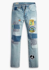 Jeans de mezclilla azul claro con varias piezas de parche, incluyendo parches bordados y un símbolo de paz; presenta diferentes texturas y patrones.
