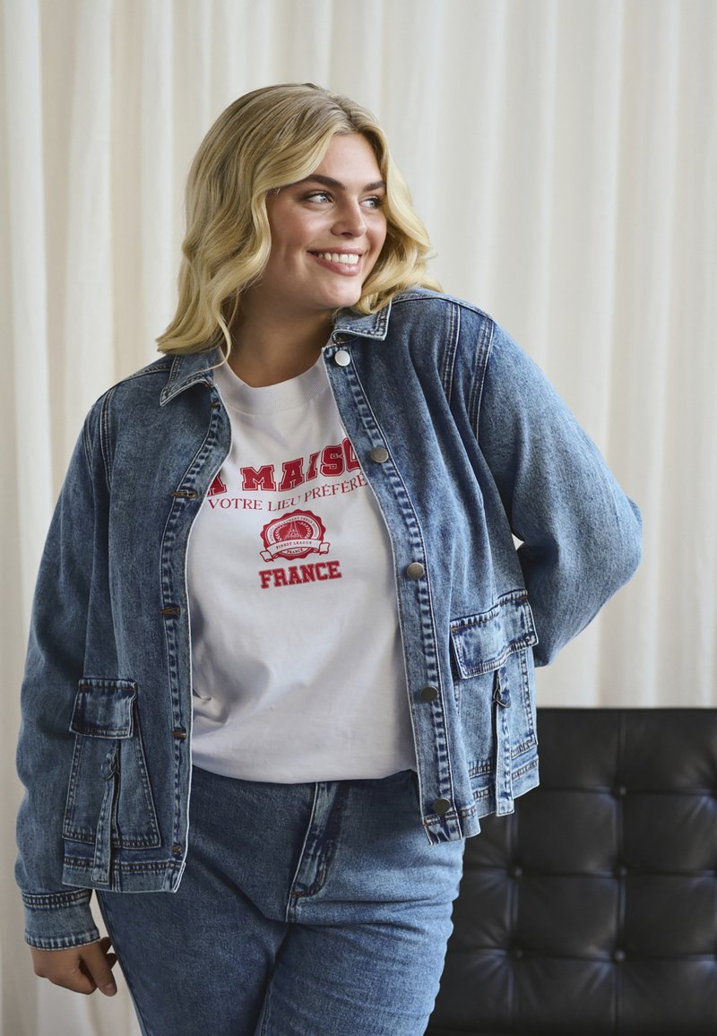 Nattblå denimjacka med avslappnad passform, med två framfickor och tryckknappar. Vit t-shirt under med röd grafisk tryck.