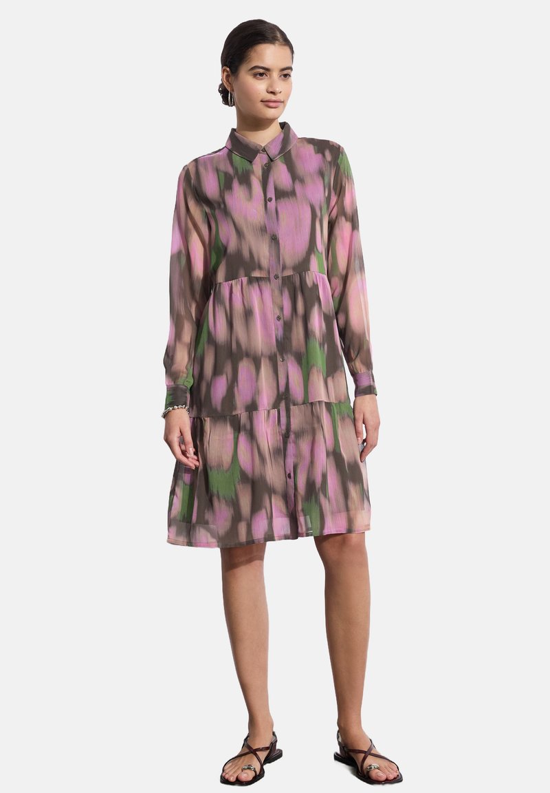 Abito a maniche lunghe e con bottoni in tessuto trasparente. Presenta un motivo rosa, verde e marrone. Design a campana con una gonna a più strati.