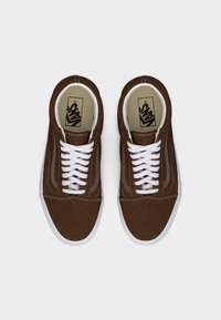 Ζευγάρι καφέ αθλητικών παπουτσιών Vans με λευκά κορδόνια και λαστιχένιες σόλες, προβολή από πάνω σε λευκό φόντο.