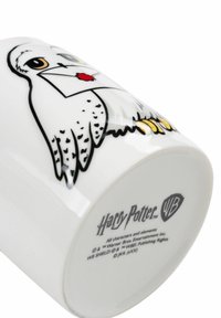 White ceramic mug featuring an illustrated owl holding a letter with a red seal, black outlines, and yellow feet. Harry Potter logo on base.