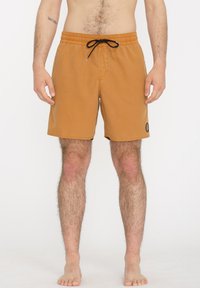 Bañadores de hombre en un color marrón claro con cinturilla elástica y cordón negro. Presentan un bolsillo lateral y un parche con logo.