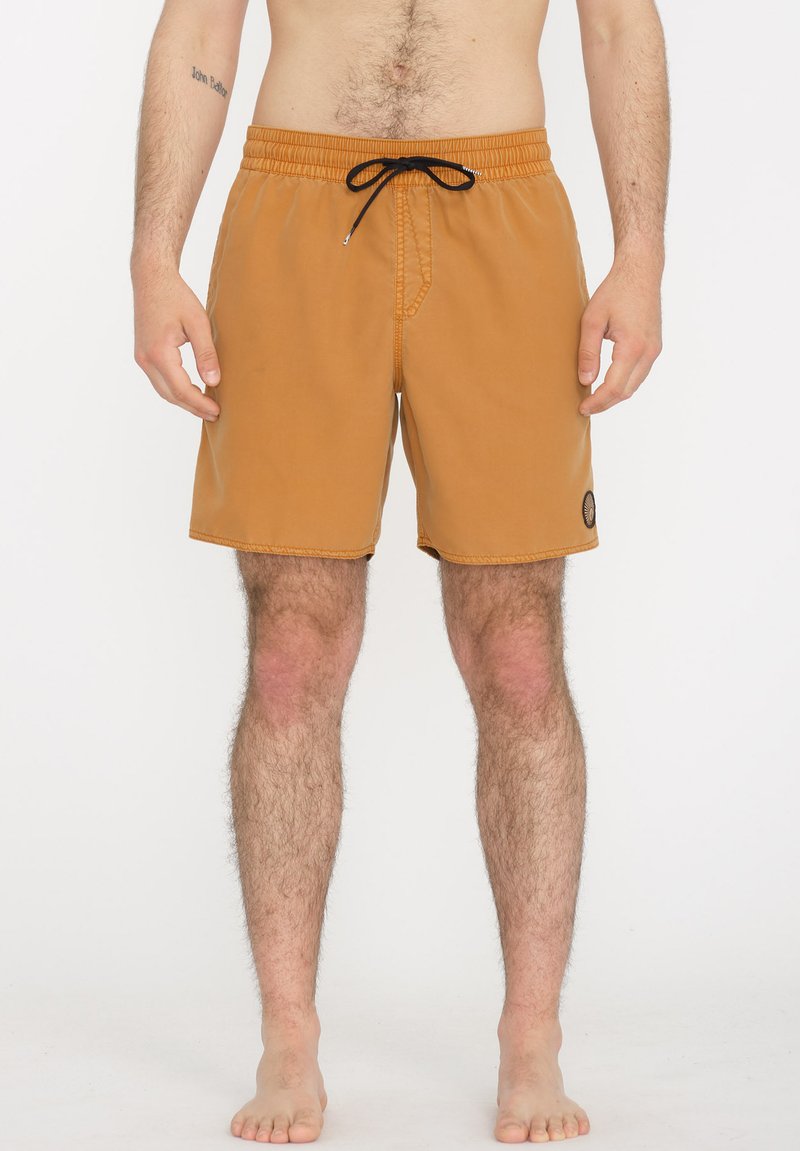 Bañadores de hombre en un color marrón claro con cinturilla elástica y cordón negro. Presentan un bolsillo lateral y un parche con logo.