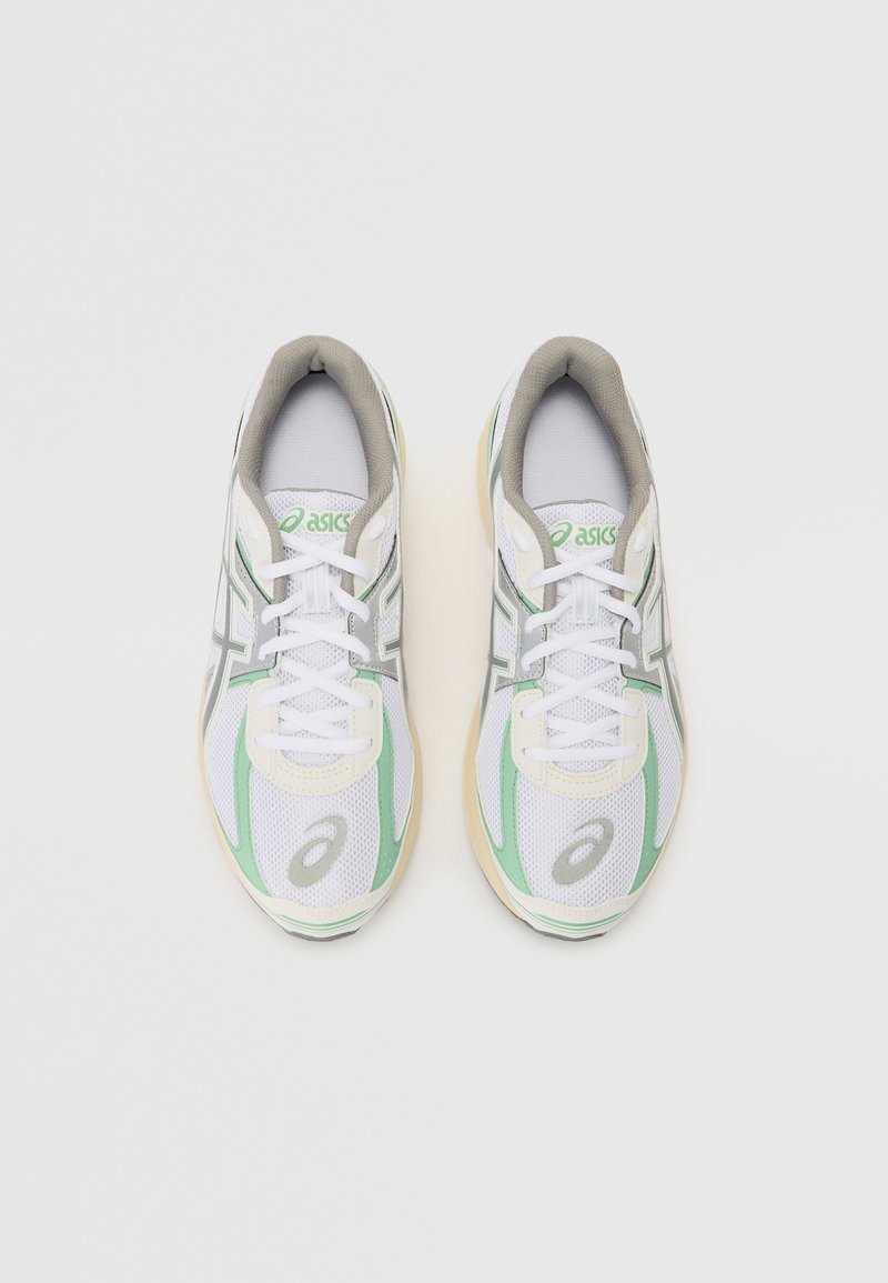 Zapatillas de running blancas con acentos verdes, que cuentan con una parte superior de malla, suela de goma y diseño de cordones. Logo destacable en la lengüeta y en el costado.