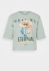 Lysegrønn avkortet t-skjorte laget av myk bomull, med et blomsterdesign og teksten "Eternal Sunshine" i fet, glitrende skrift.