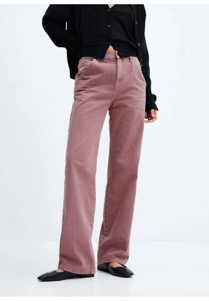 Osoba nosząca szerokie spodnie z wysokim stanem w kolorze mauve, czarny zapinany na guziki kardigan i czarne baleriny, stojąca na jednolitym białym tle.