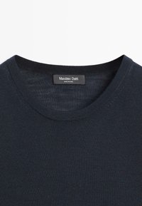 Pull tricoté bleu marine à col rond avec une étiquette noire Massimo Dutti cousue à l'intérieur du col, fabriqué en Chine.