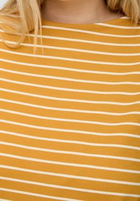 Tissu rayé jaune avec des lignes blanches horizontales. Texture lisse, présentant un design simple et un décolleté décontracté.
