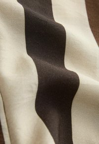 Gros plan sur un tissu lisse avec de larges rayures verticales alternées marron foncé et beige, avec une texture visible.