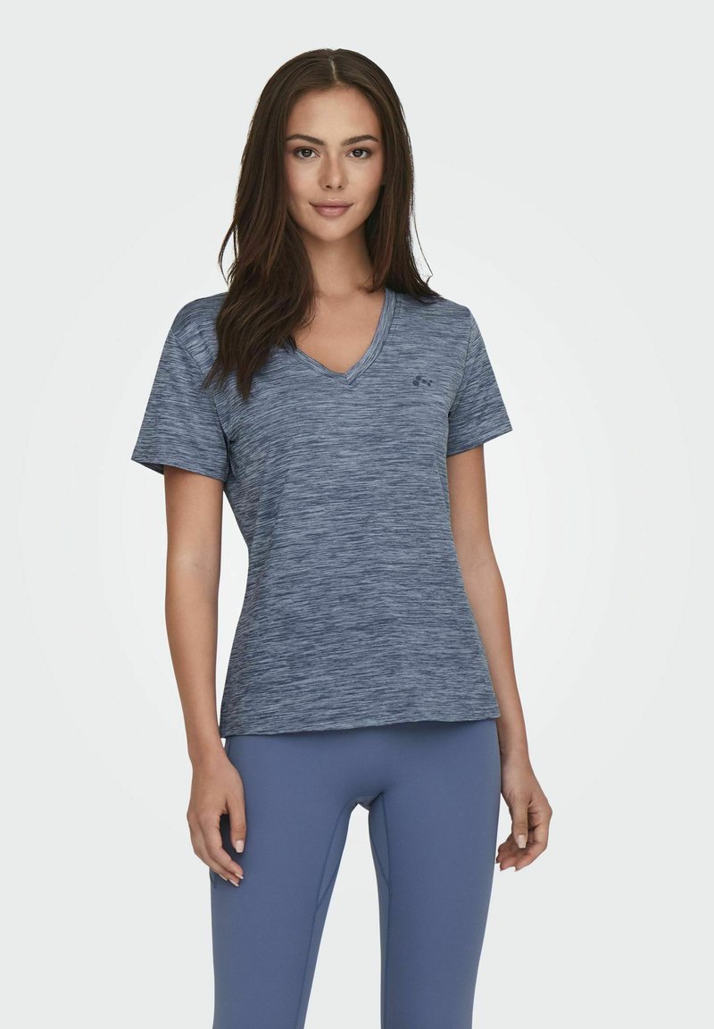 Koszulka sportowa z dekoltem w serek w melanzowym granatowym kolorze, krótki rękaw i lekko dopasowany krój, w zestawieniu z jasnoniebieskimi legginsami.