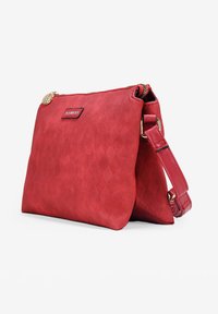 Bolso de mano rojo hecho de un material texturizado con un patrón de diamantes, que cuenta con un cierre de cremallera, correa ajustable y acentos metálicos.