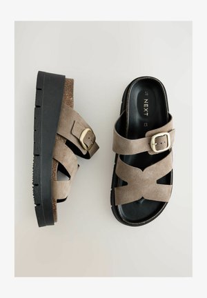 Sandales en daim marron à semelle plateforme en caoutchouc noir, dotées de brides croisées et d'un accent de boucle en or.