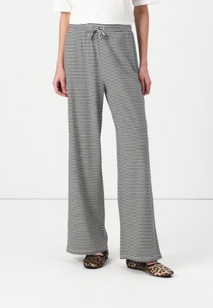Pantalons à larges rayures noires et blanches avec un taille élastique à cordon, fabriqués à partir d'un tissu doux, associés à des ballerines au motif animal.