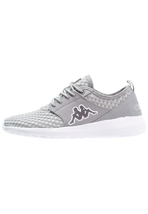 Chaussure de sport en mesh gris clair avec semelle blanche et lacets sur le devant, présentant un logo noir et blanc de deux personnages assis sur le côté.