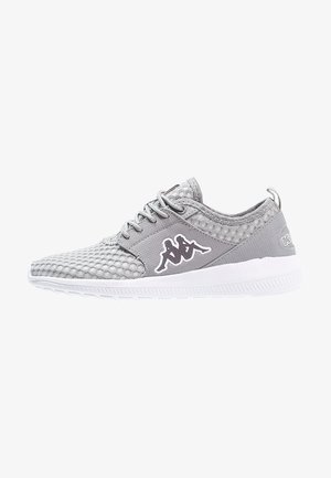 Chaussure de sport en mesh gris clair avec semelle blanche et lacets sur le devant, présentant un logo noir et blanc de deux personnages assis sur le côté.