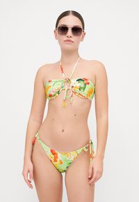 Kylpytakki, jossa on kukkakuvioita vihreänä, sisältää säädettävän solmimisnauhan ja siihen sopivat matalat alushousut sivusiteillä.