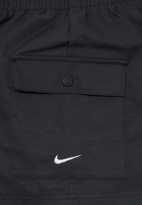 Černé Nike šortky s zadní kapsou na cvok a bílým logem Nike. Vyrobené z lehkého tkaného materiálu s hladkou texturou.