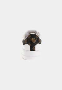 Białe sneakersy z czarnym, teksturowanym zapiętkiem, z złotym logo i wzorem. Gładka powierzchnia cholewki z zaokrąglonym czubkiem i płaską, białą podeszwą.