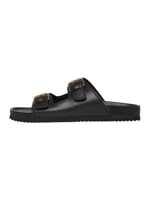 Czarna sandałka na płaskiej podeszwie z dwoma regulowanymi paskami z brązowymi klamrami i teksturowaną podeszwą zapewniającą przyczepność, widziana z boku.