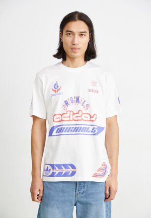 Witte katoenen t-shirt met gedurfde, multicolore "adidas" branding en logo's, met grafische accenten in rood, blauw en paars. Korte mouwen, relaxte fit.