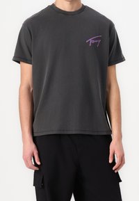 Grå bomullströja med avslappnad passform, korta ärmar och rundad halsringning. Har en flerfärgad "Tommy"-logotyp på vänster bröst.