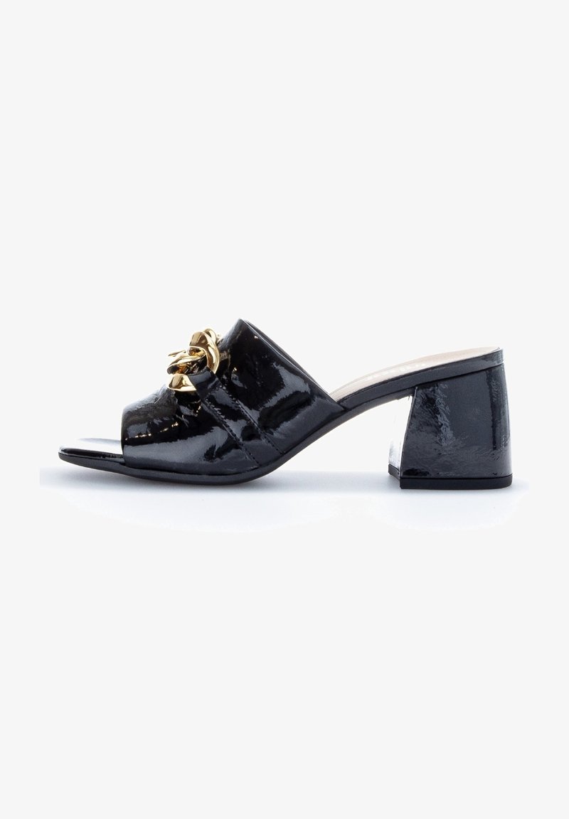 Mule en cuir verni noir à bout ouvert, talon bloc et chaîne décorative dorée sur la bride supérieure.