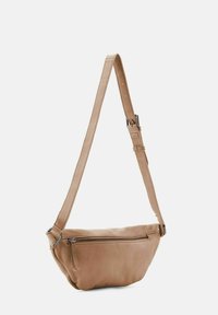 Bolso cruzado de cuero marrón con una textura suave, bolsillo frontal con cremallera y correa ajustable. Forma redondeada con sutiles detalles de costura.