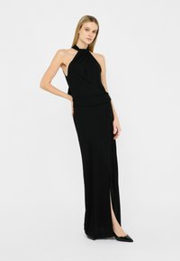Zwarte halterneck jurk met een aansluitende top en een lange, vloeiende rok met een zijspleet. Glad, stretchy materiaal met een elegante afwerking.