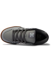 Scarpe da skate grigie realizzate in materiale sintetico con linguetta imbottita, punta perforata e lacci grigio scuro. Suola in gomma con accenti marroni.