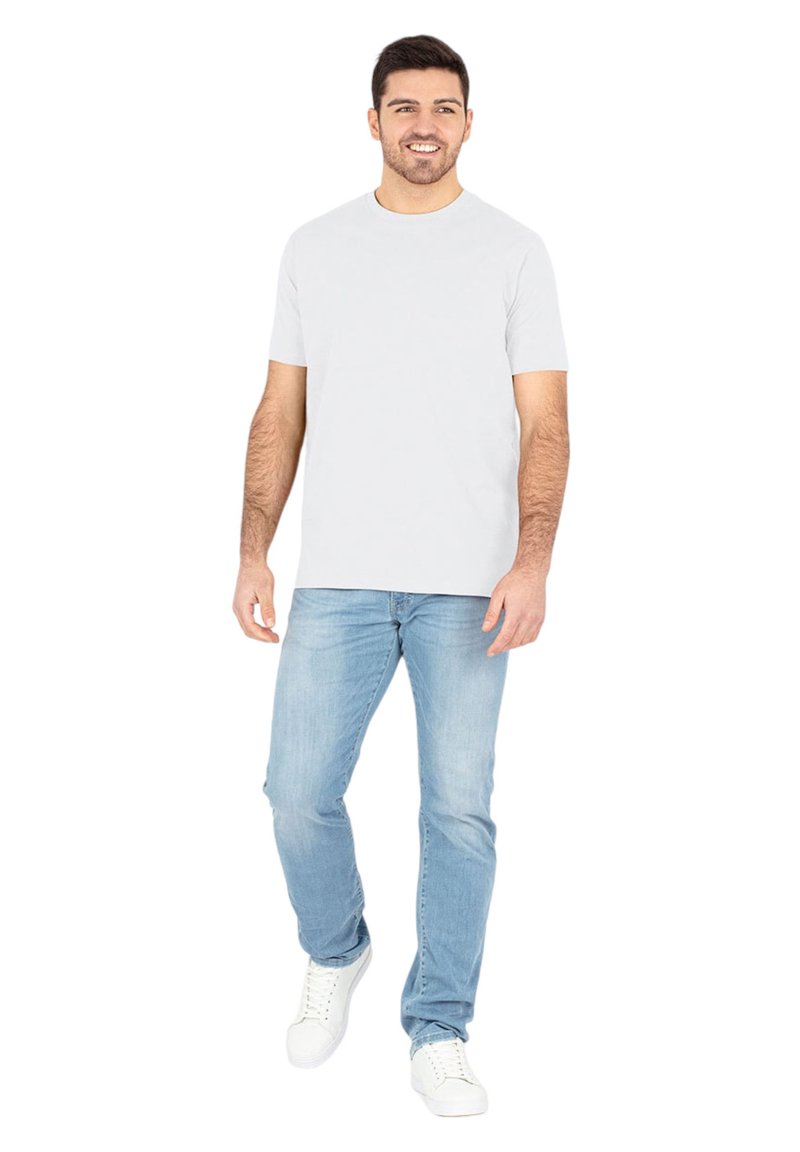 Helles graues Baumwoll-T-Shirt mit kurzen Ärmeln, kombiniert mit hellblauen Jeans und weißen Turnschuhen. Steht vor einem weißen Hintergrund.