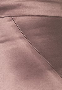 Satinowy materiał w stonowanym kolorze mauve, z ukośnym detalem szwu i gładką fakturą. Powierzchnia wydaje się lekko połyskująca.