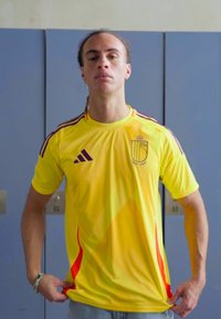 Yellow athletic shirt with red accents and vertical stripes, featuring a logo on the chest. Made of soft, breathable fabric.
