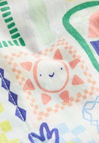 Buntes Stoffmuster mit verspielten Motiven, darunter eine lächelnde Sonne, geometrische Formen und gitterartige Designs in Pink, Grün, Blau und Gelb.