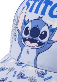 Casquette bleu clair avec un design de dessin animé de Stitch, incluant des palmiers et du texte. Le matériau semble être un tissu avec des détails de couture.