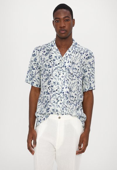Korte mouwen shirt van lichtgewicht stof met een blauw bloemenpatroon op een lichte achtergrond, gecombineerd met witte broeken.