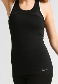 Débardeur de sport noir avec un design en mesh au niveau du col, présentant une coupe ajustée et un petit logo Nike argenté en bas à l'avant.